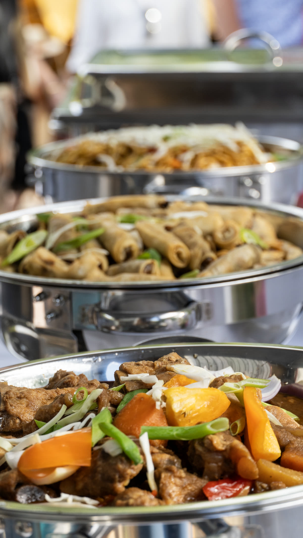 Filipino lumpia, beef caldereta and stir-fried dishes in chafing dishes